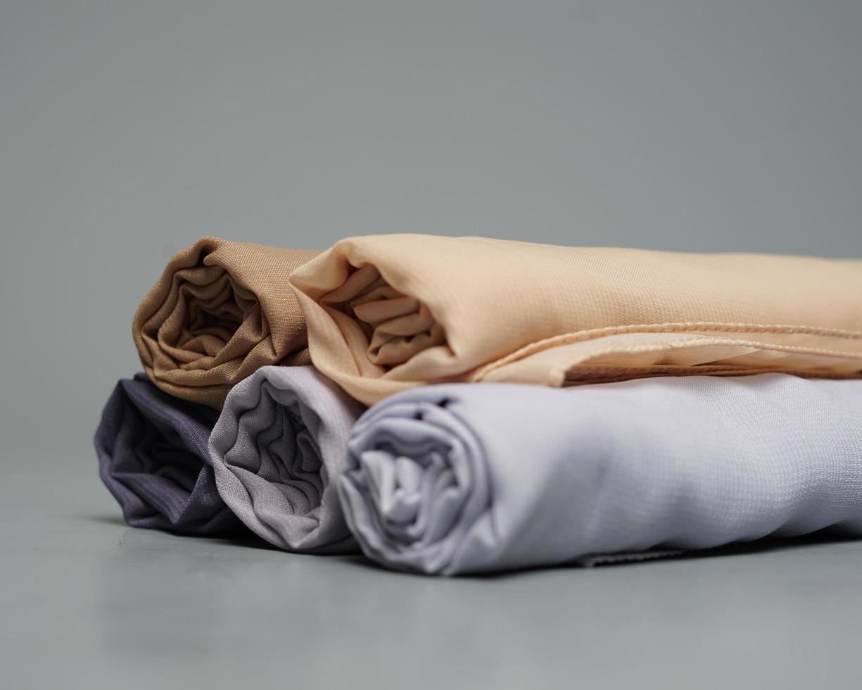 A roll of nude colored veil is neatly arranged on a gray background. Rolls of thin gray fabric that are ready to be used for Muslim women. Can also be used for sales displays. focus blur. hijab women. photo