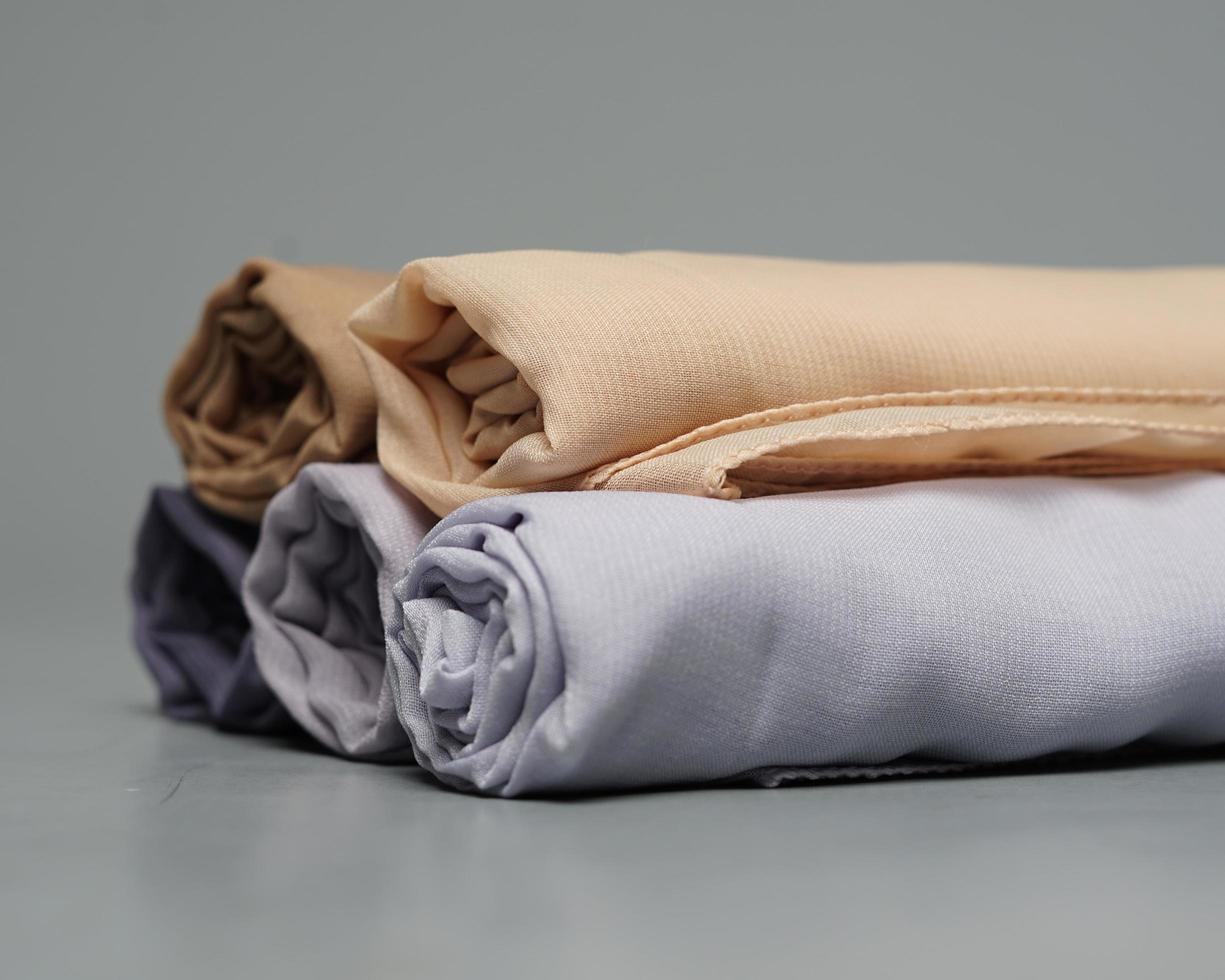 A roll of nude colored veil is neatly arranged on a gray background. Rolls of thin gray fabric that are ready to be used for Muslim women. Can also be used for sales displays. focus blur. hijab women. photo