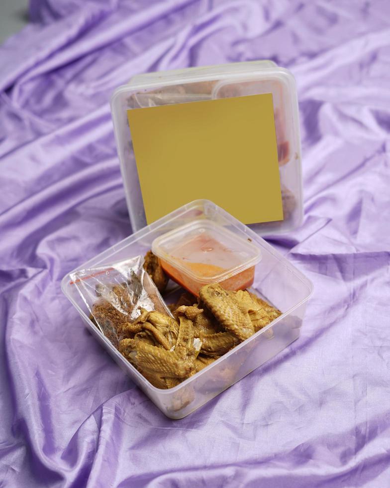 pollo envuelto con especias indonesias. los trozos de pollo están listos para ser fritos. comida lista para comer en caja de embalaje completa con salsa de chile, etc. caja de maqueta de embalaje de alimentos para plantilla. desenfoque de enfoque foto