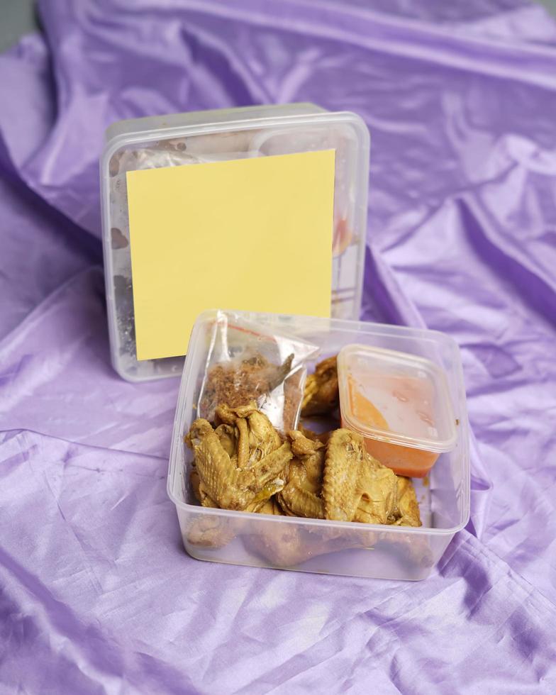 Chicken wrapped with Indonesian spices. Chicken pieces are ready to be fried. Ready-to-eat food in box packaging complete with chili sauce etc. Food packaging mockup box for template. Focus blur. photo