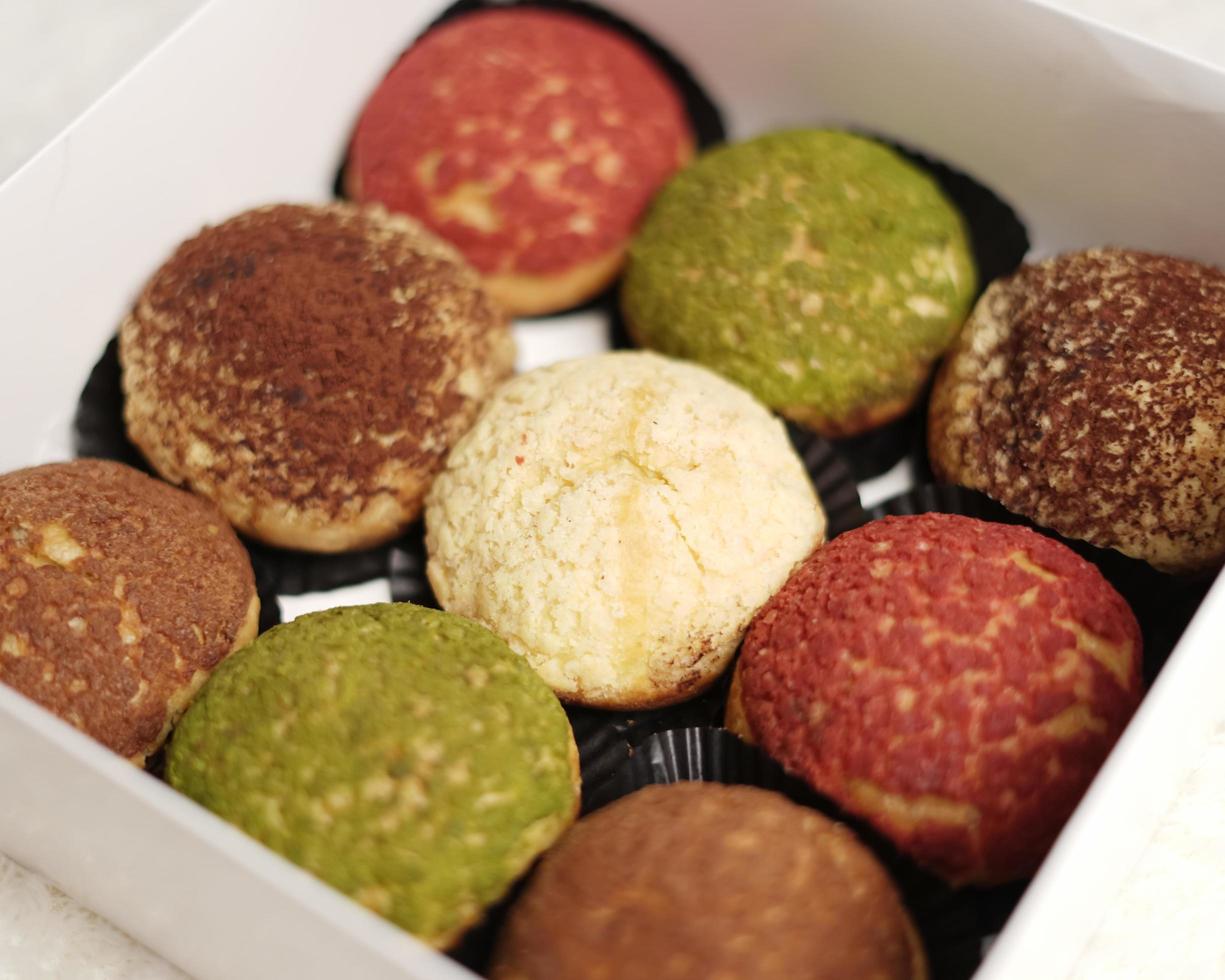 El craquelin choux es un canutillo japonés con una capa crujiente que tiene un sabor dulce y cremoso. creampuffs que contienen varios sabores de fla, vainilla, chocolate, matcha. eid cestas o paquetes. desenfoque de enfoque foto