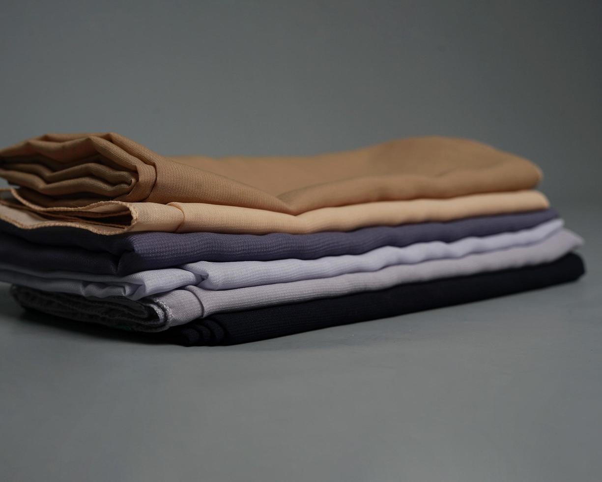 Stacks of nude colored veils neatly arranged on a gray background. Thin fabric blend of gray color that is ready to be used for Muslim women. Can also be used for sales displays. focus blur. hijab. photo