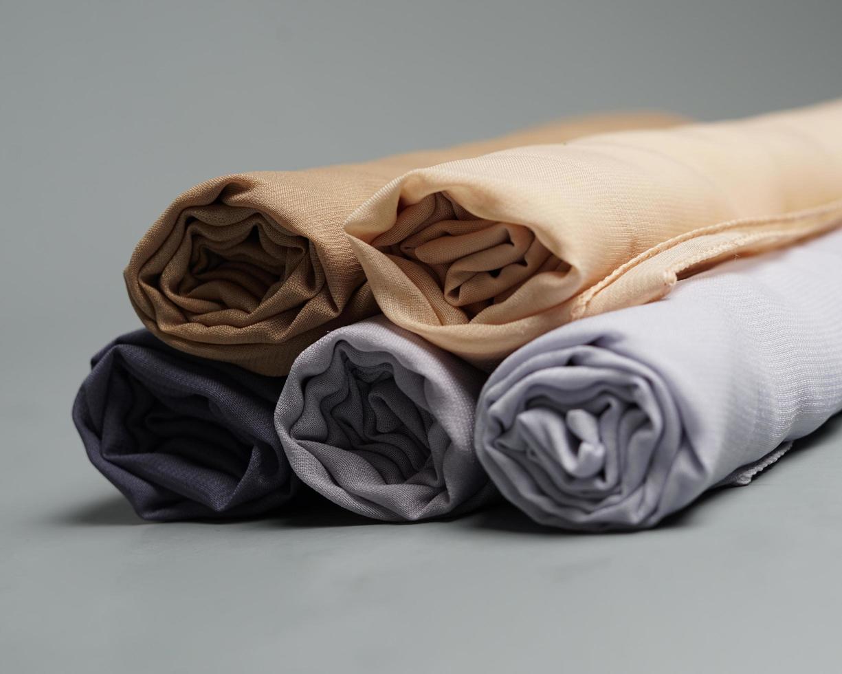 A roll of nude colored veil is neatly arranged on a gray background. Rolls of thin gray fabric that are ready to be used for Muslim women. Can also be used for sales displays. focus blur. hijab women. photo