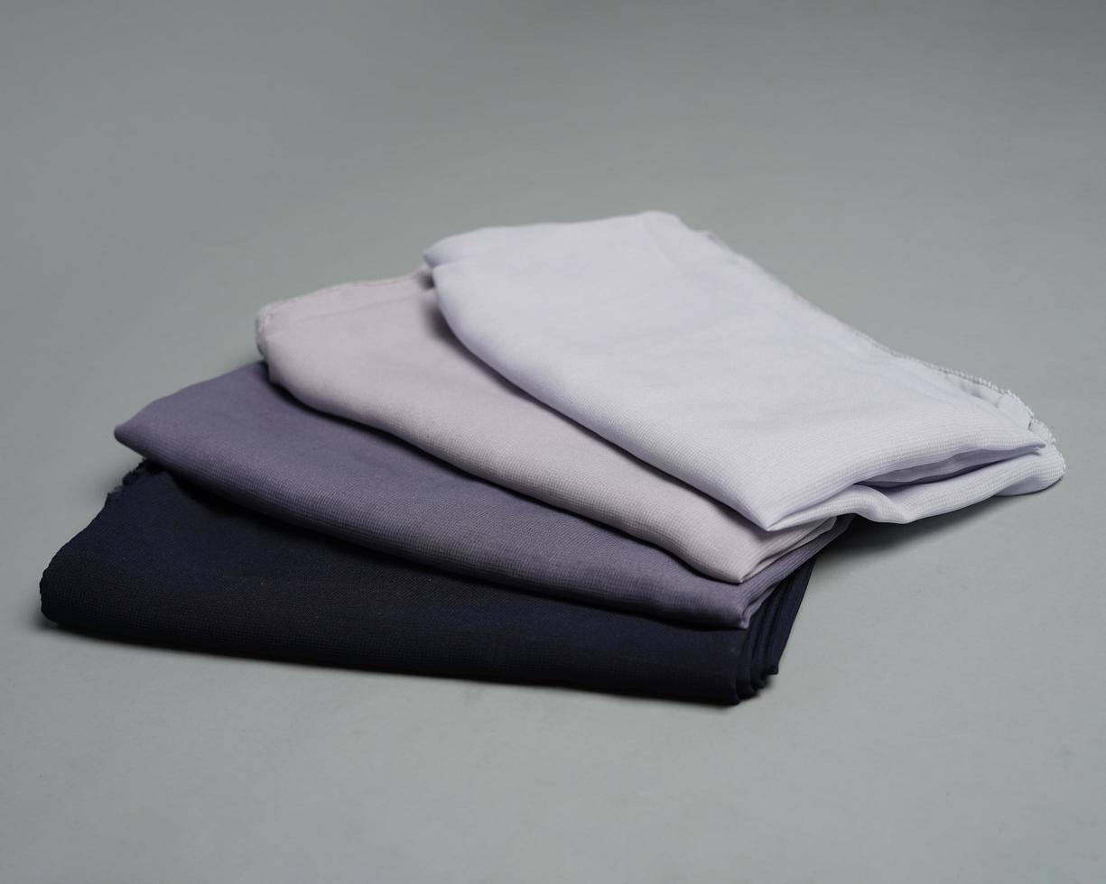 Stacks of nude colored veils neatly arranged on a gray background. Thin fabric blend of gray color that is ready to be used for Muslim women. Can also be used for sales displays. focus blur. hijab. photo