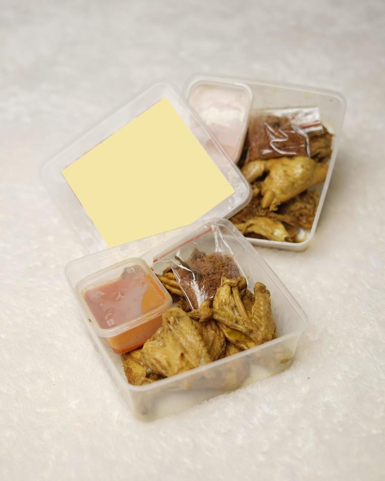 Chicken wrapped with Indonesian spices. Chicken pieces are ready to be fried. Ready-to-eat food in box packaging complete with chili sauce etc. Food packaging mockup box for template. Focus blur. photo