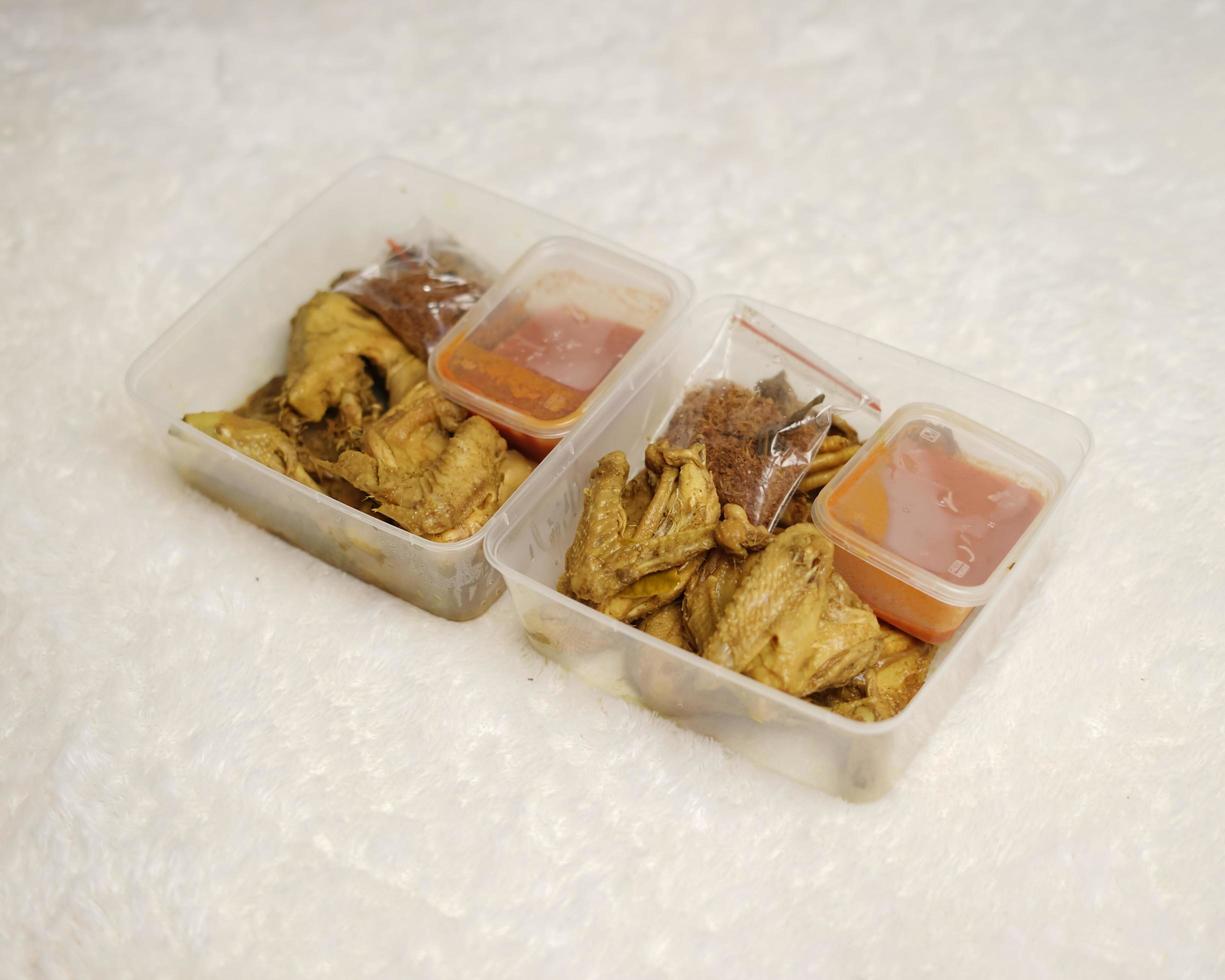 pollo envuelto con especias indonesias. los trozos de pollo están listos para ser fritos. comida lista para comer en caja de embalaje completa con salsa de chile, etc. caja de maqueta de embalaje de alimentos para plantilla. desenfoque de enfoque foto