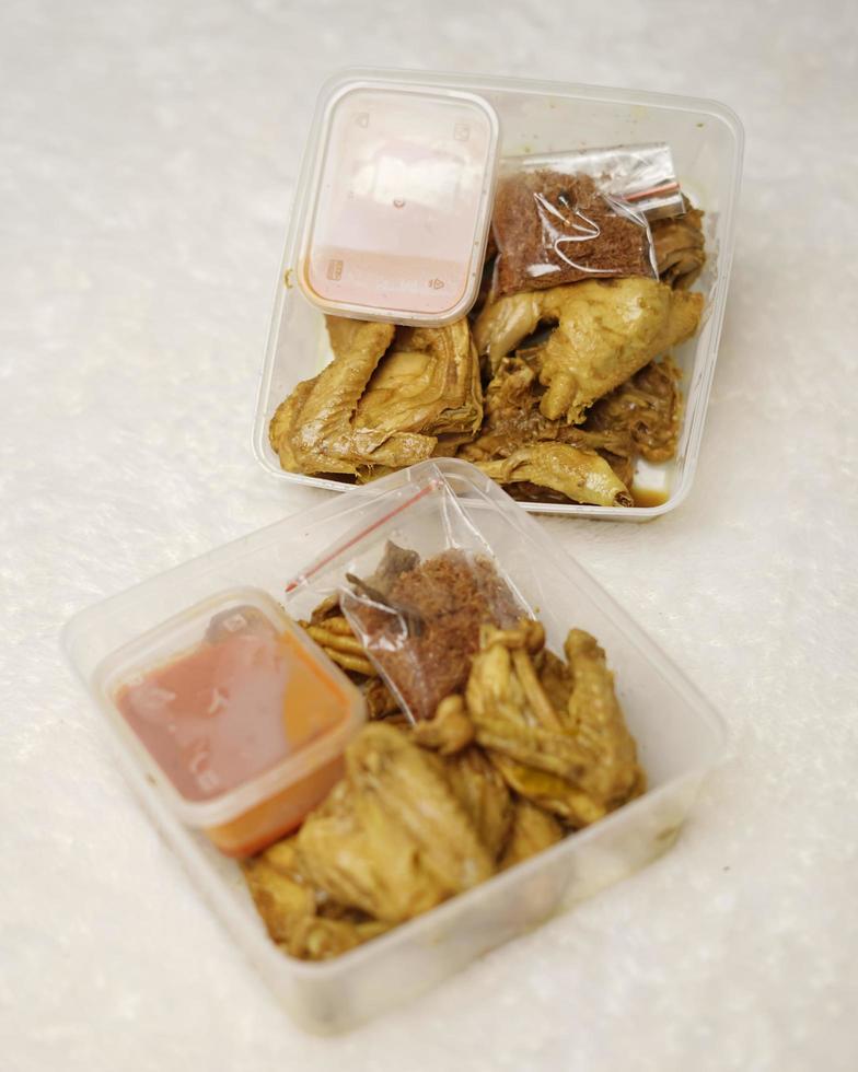 Chicken wrapped with Indonesian spices. Chicken pieces are ready to be fried. Ready-to-eat food in box packaging complete with chili sauce etc. Food packaging mockup box for template. Focus blur. photo