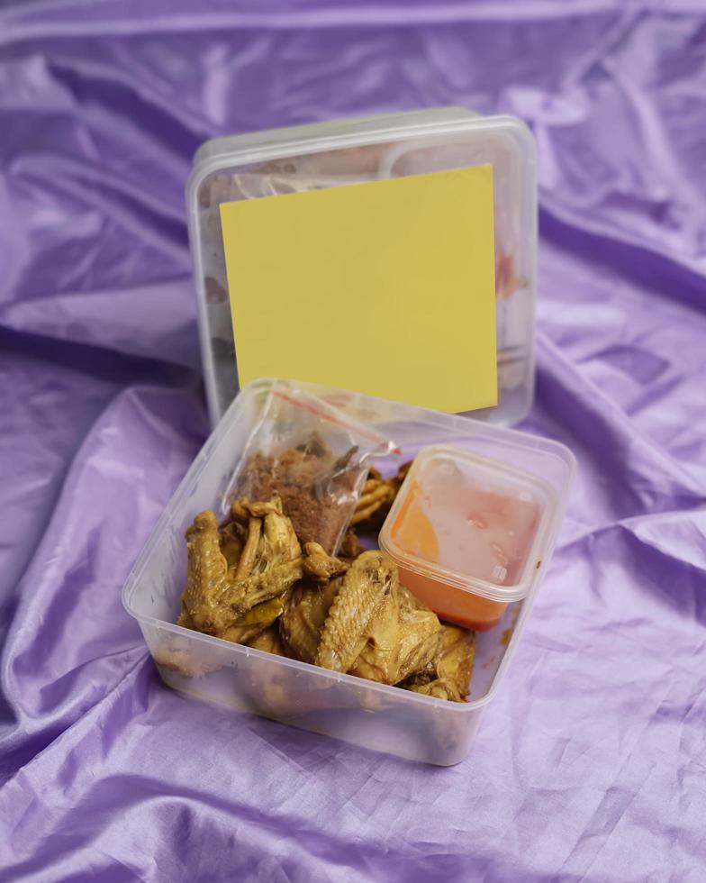 pollo envuelto con especias indonesias. los trozos de pollo están listos para ser fritos. comida lista para comer en caja de embalaje completa con salsa de chile, etc. caja de maqueta de embalaje de alimentos para plantilla. desenfoque de enfoque foto