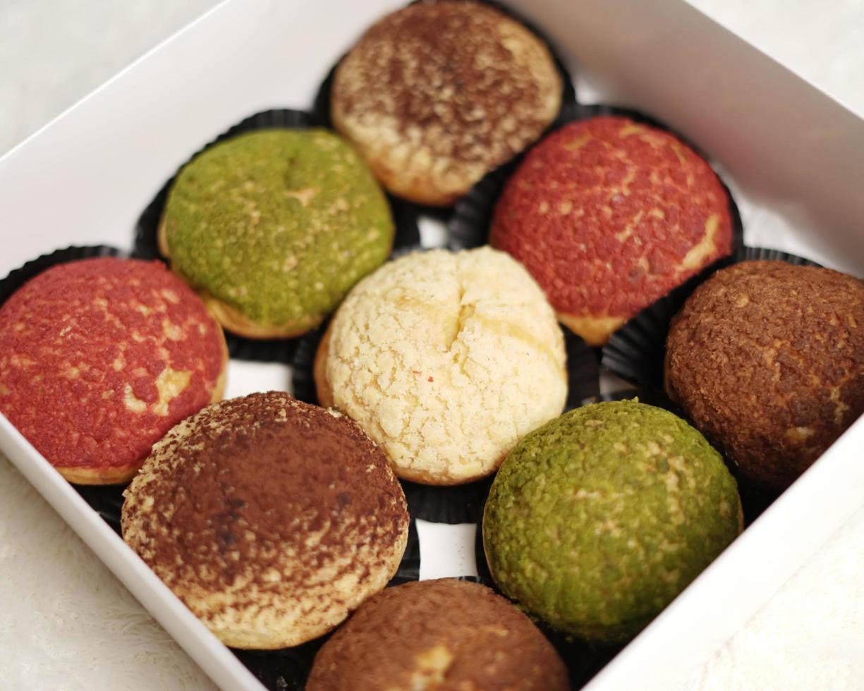 Craquelin choux is a Japanese eclairs with a crispy coating that tastes sweet and creamy. Creampuffs containing various flavors of fla, vanilla, chocolate, matcha. Eid hampers or parcels. focus blur. photo