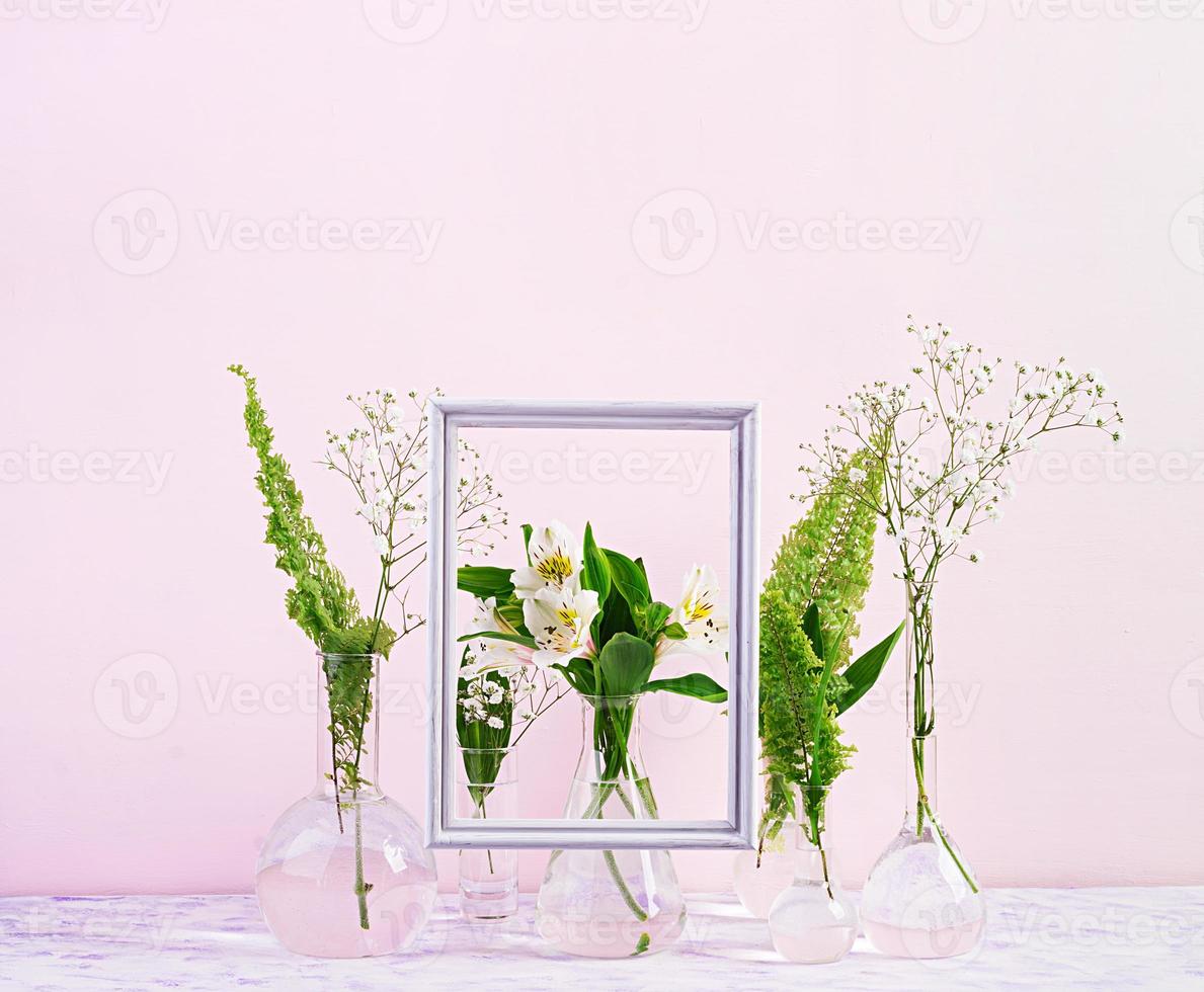 Flowers and plants in flask with frame. Beautiful spring background with flowers in vase. photo