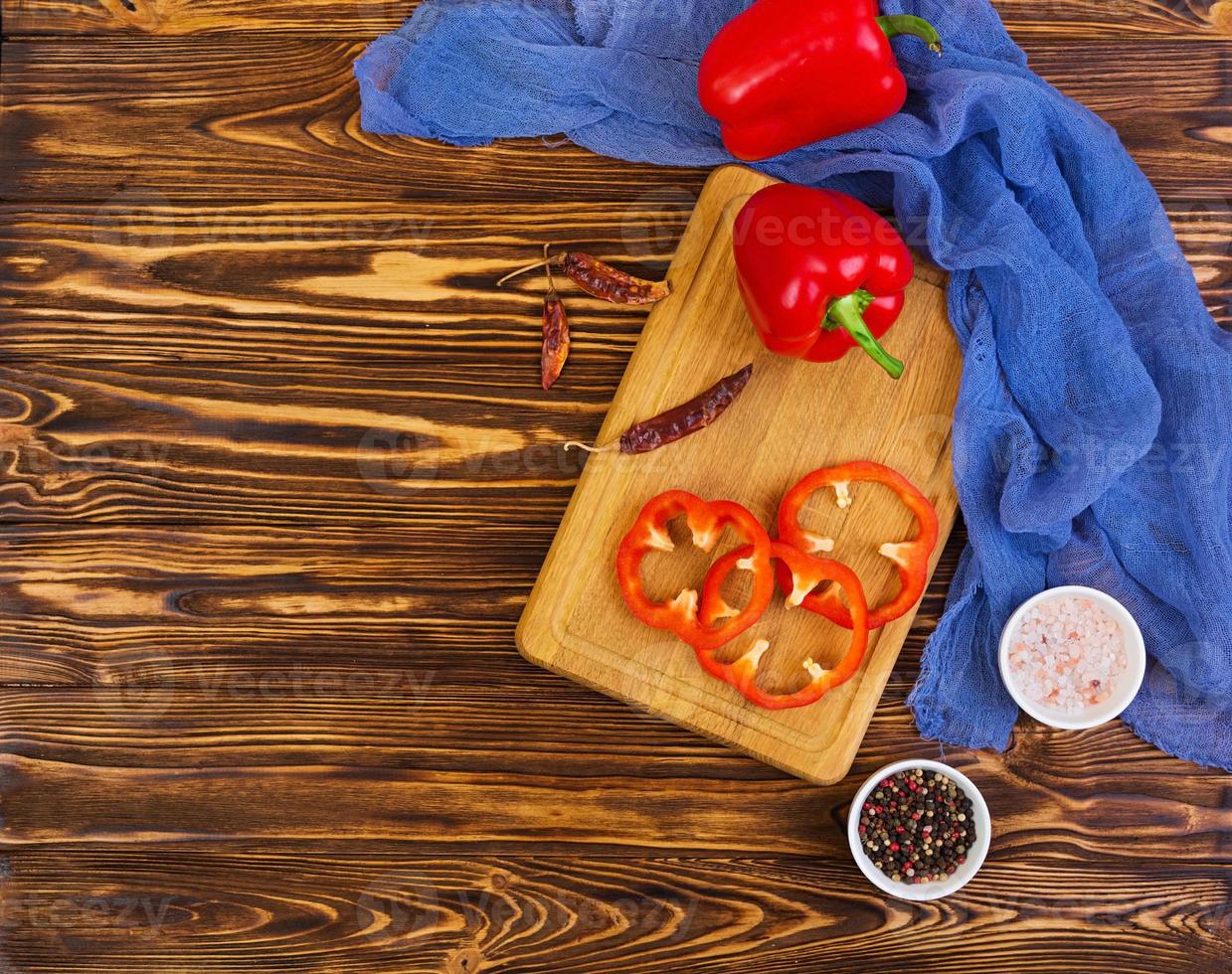 Pepper, tomato, salt, different spice on wooden background photo