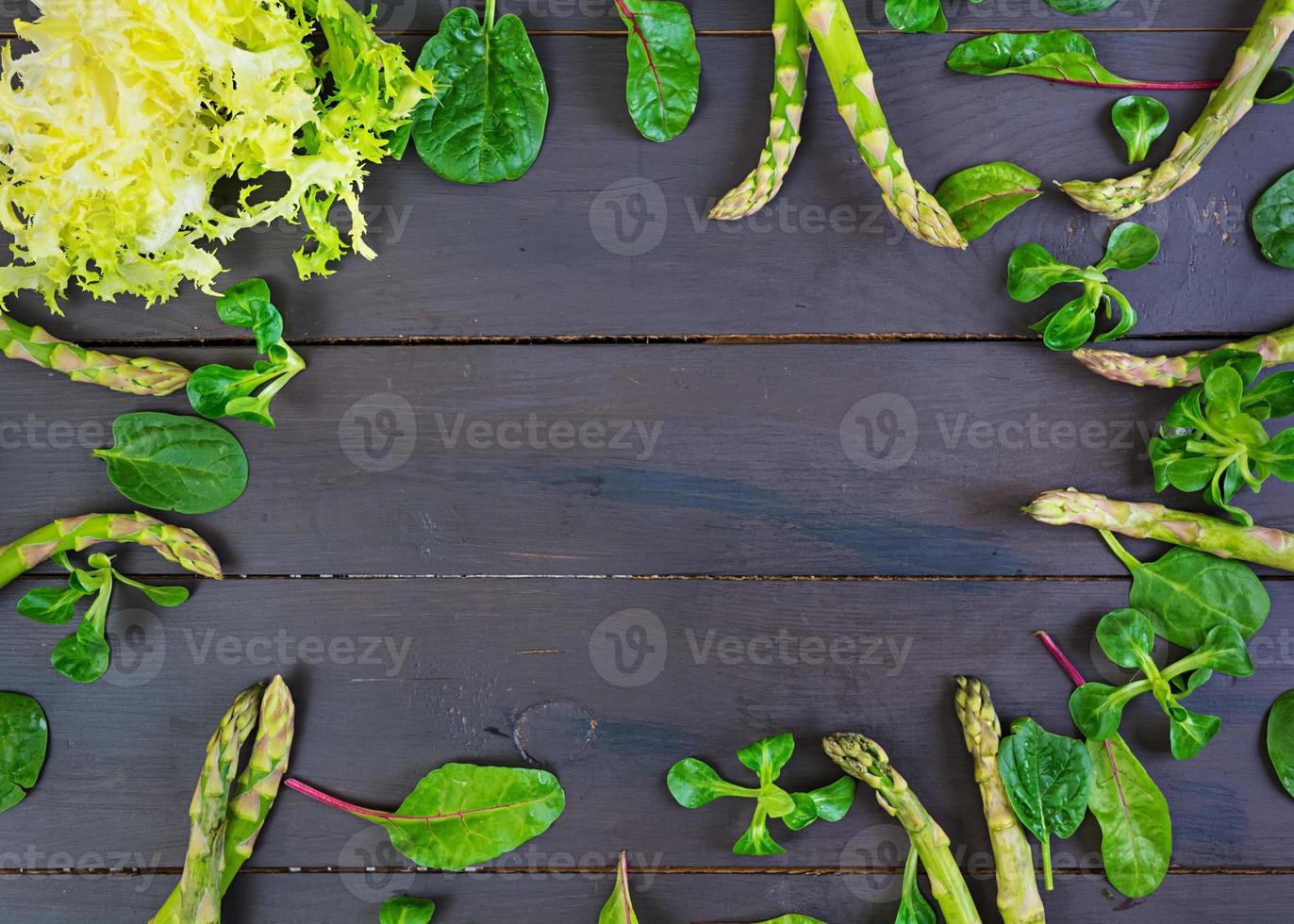 Fresh asparagus and green herbs on dark background. Top view photo