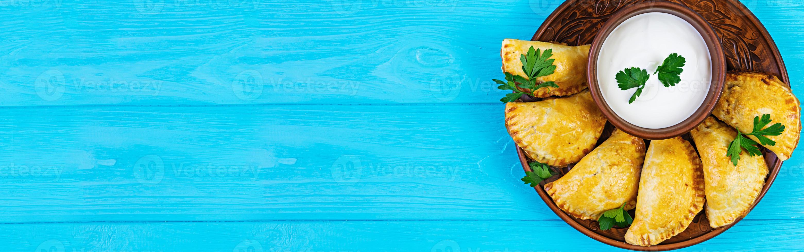 Delicious baked empanadas on wooden background. Top view. Banner. photo