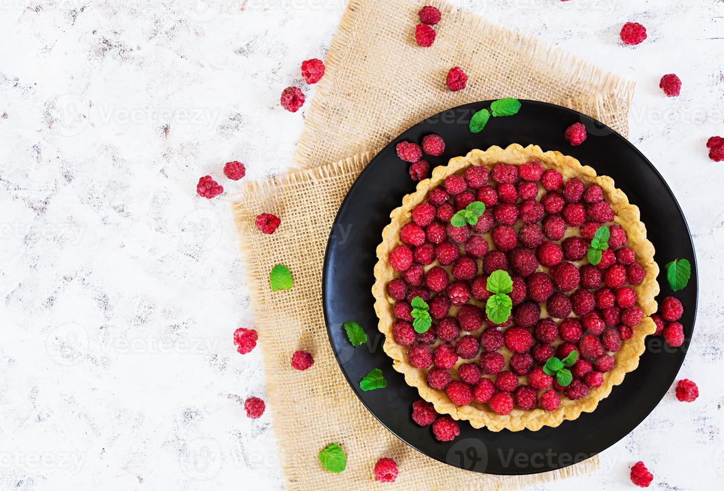 Delicious tart with custard and raspberry on wooden background photo