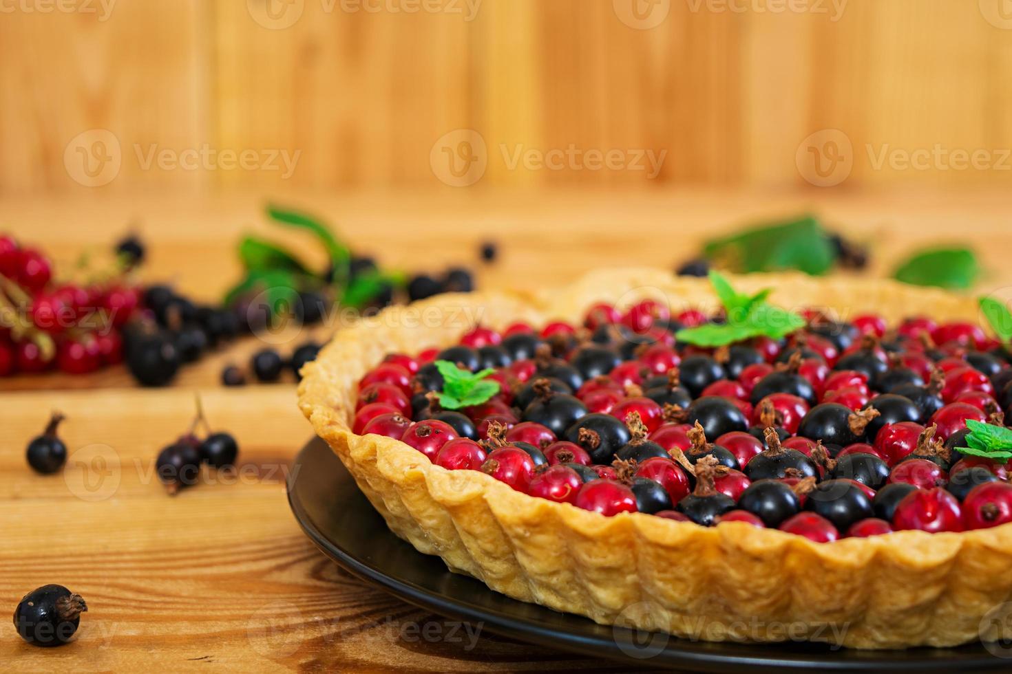 Delicious tart with custard and currant on wooden background photo