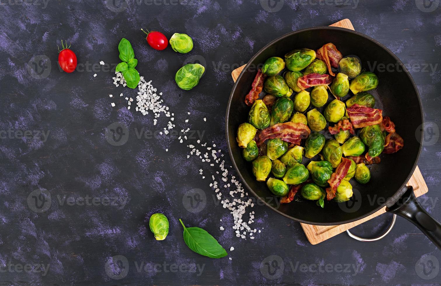 Roasted brussels sprouts with bacon on dark background. Top view photo