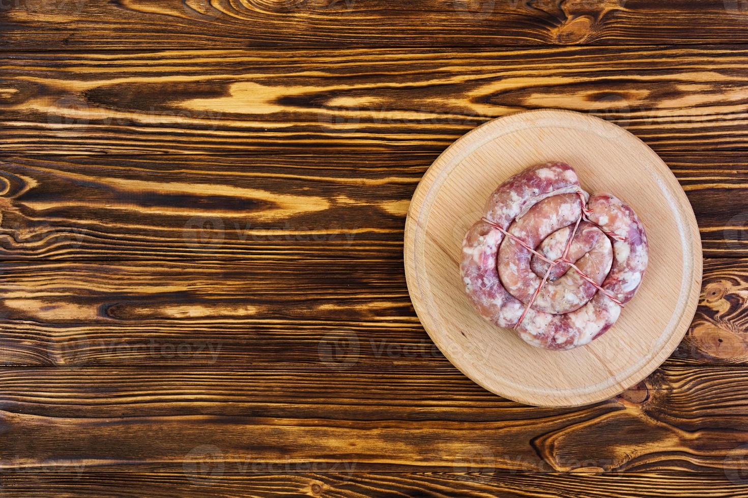 Fresh raw sausage on wooden background photo