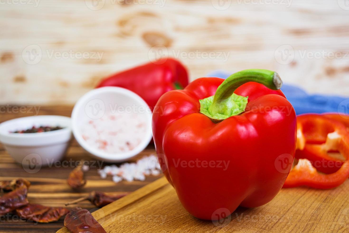 Pepper, tomato, salt, different spice on wooden background photo