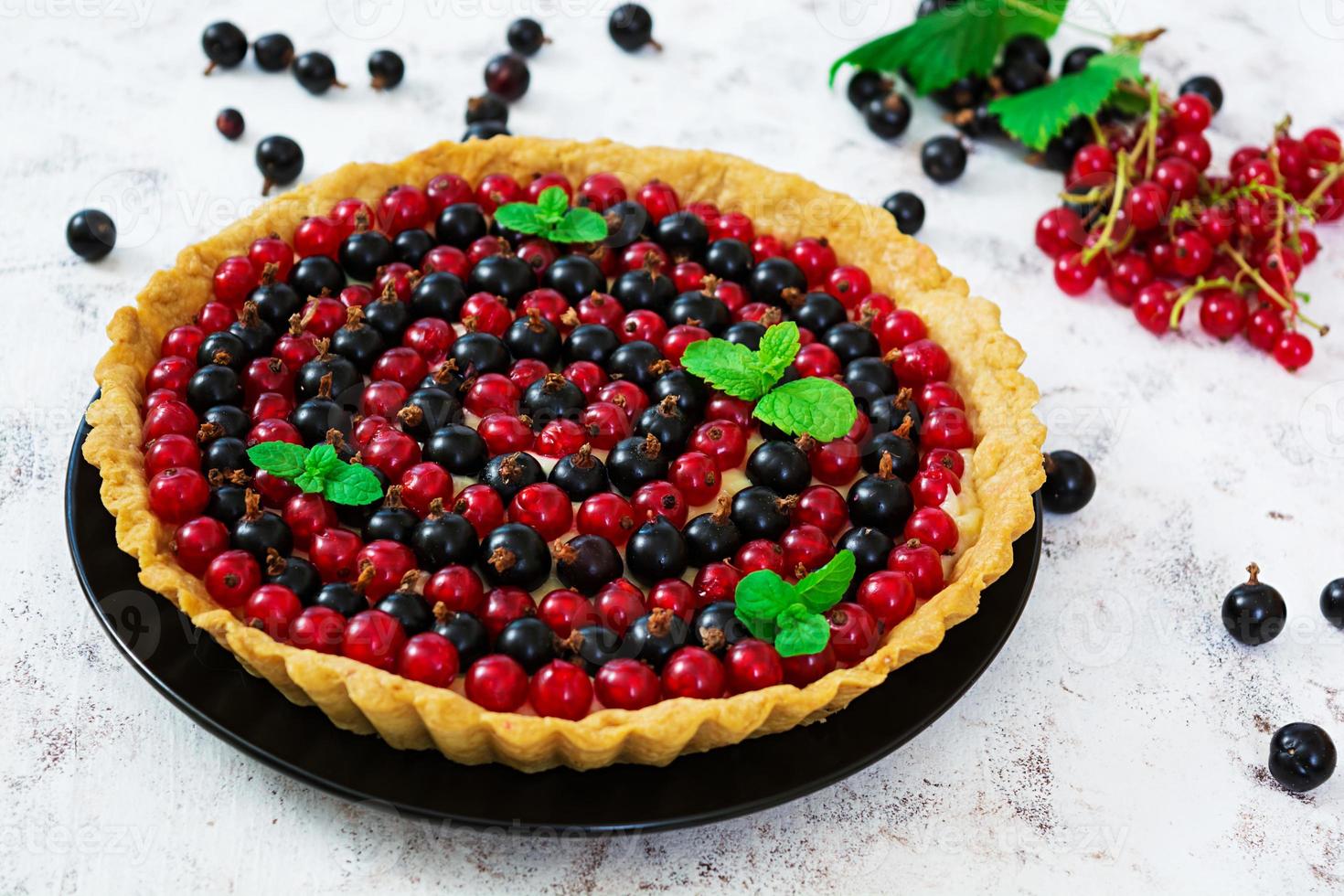 deliciosa tarta con natillas y grosellas sobre fondo blanco foto