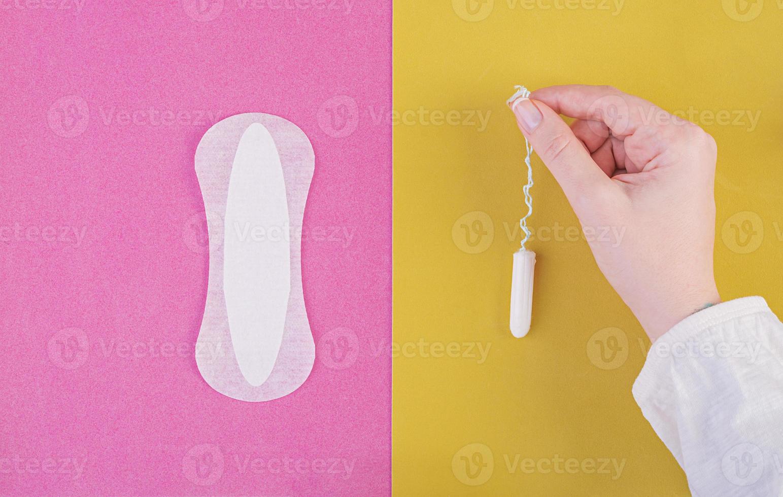 Hygiene care during critical days. Choosing between a tampon and a sanitary pad. Menstrual cycle. The woman holds in hands of a tampon. Top view photo