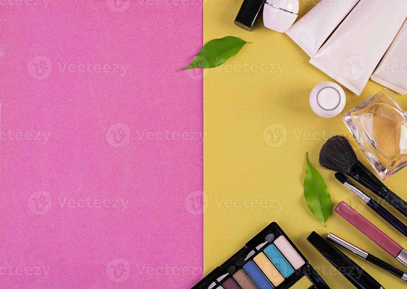 Makeup cosmetics on pink-yellow background. Top view. Copy space photo