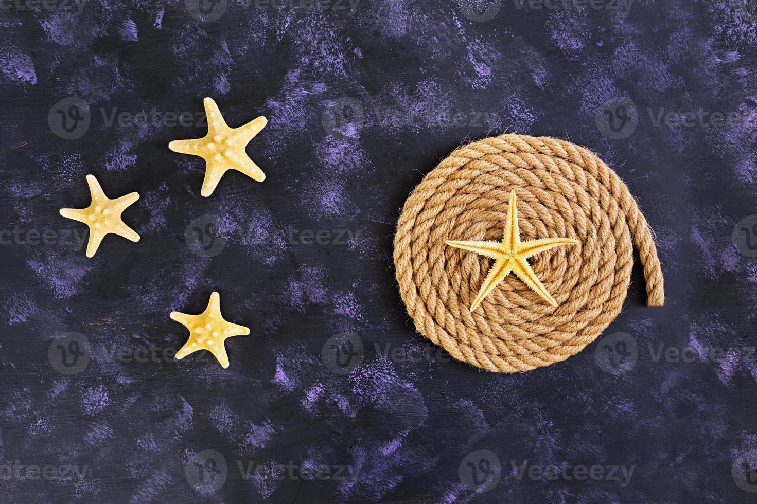 Rope and starfish on dark background. Top view photo
