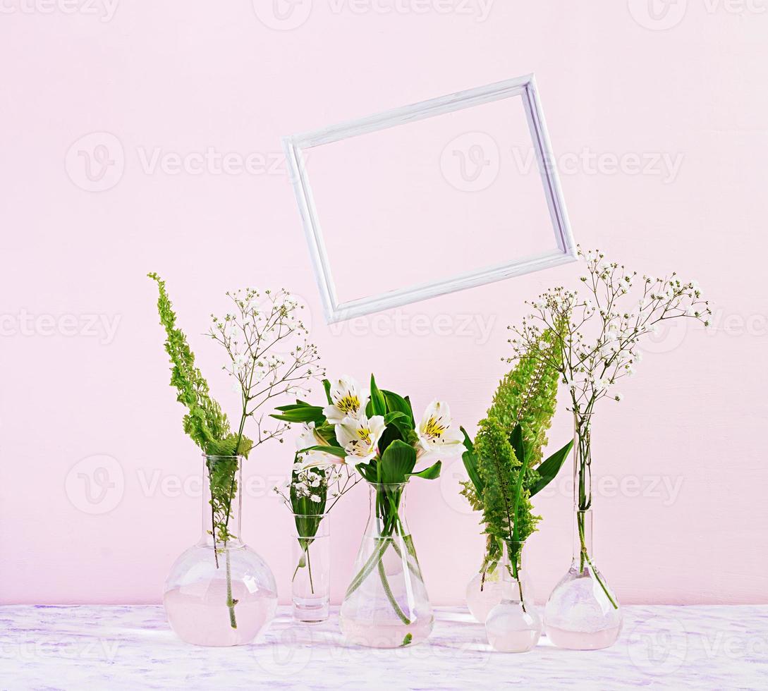 Flowers and plants in flask with frame. Beautiful spring background with flowers in vase. photo