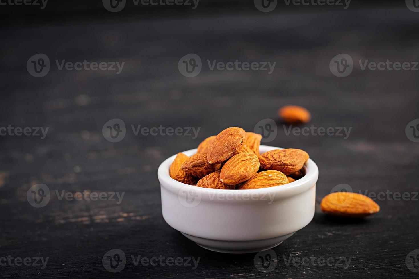 Almonds on dark wooden background. A handful of nuts. photo