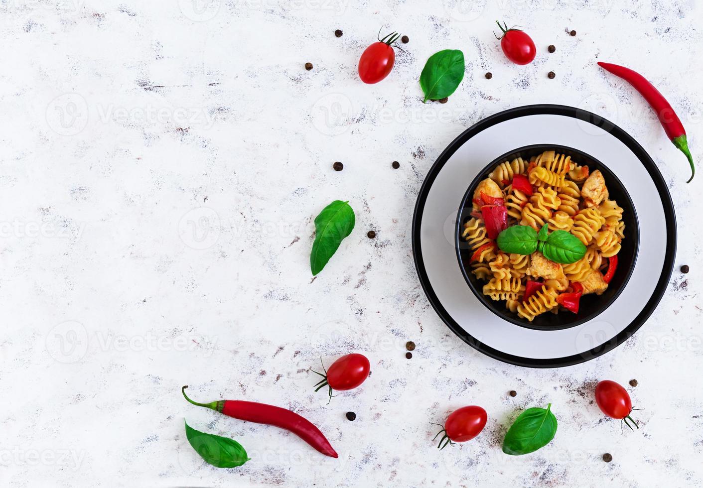 pasta radiatori con pollo y pimientos sobre fondo blanco. vista superior foto