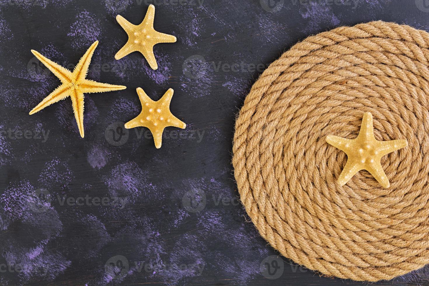 Rope and starfish on dark background. Top view photo