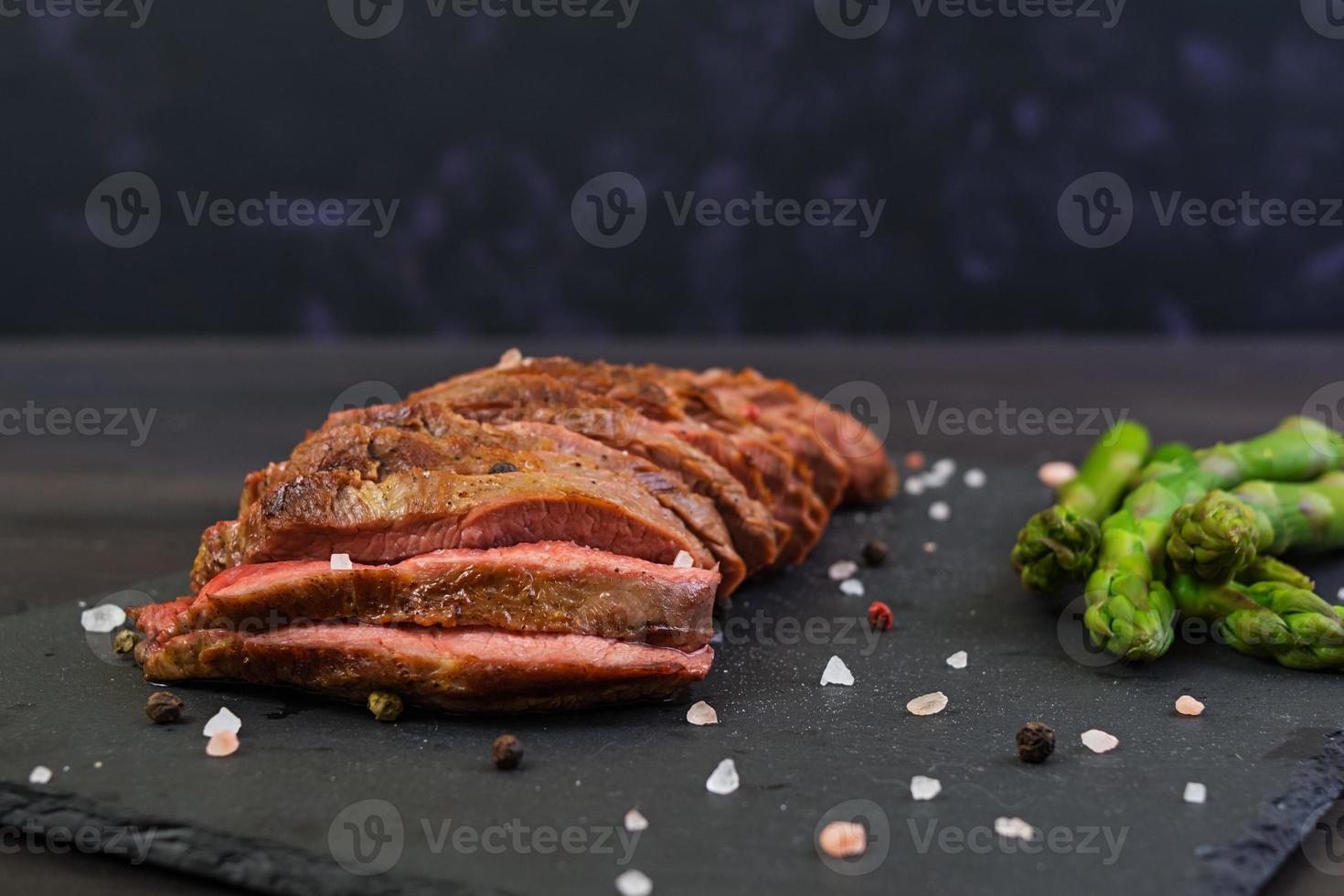 filete de ternera a la parrilla y espárragos sobre fondo de madera foto