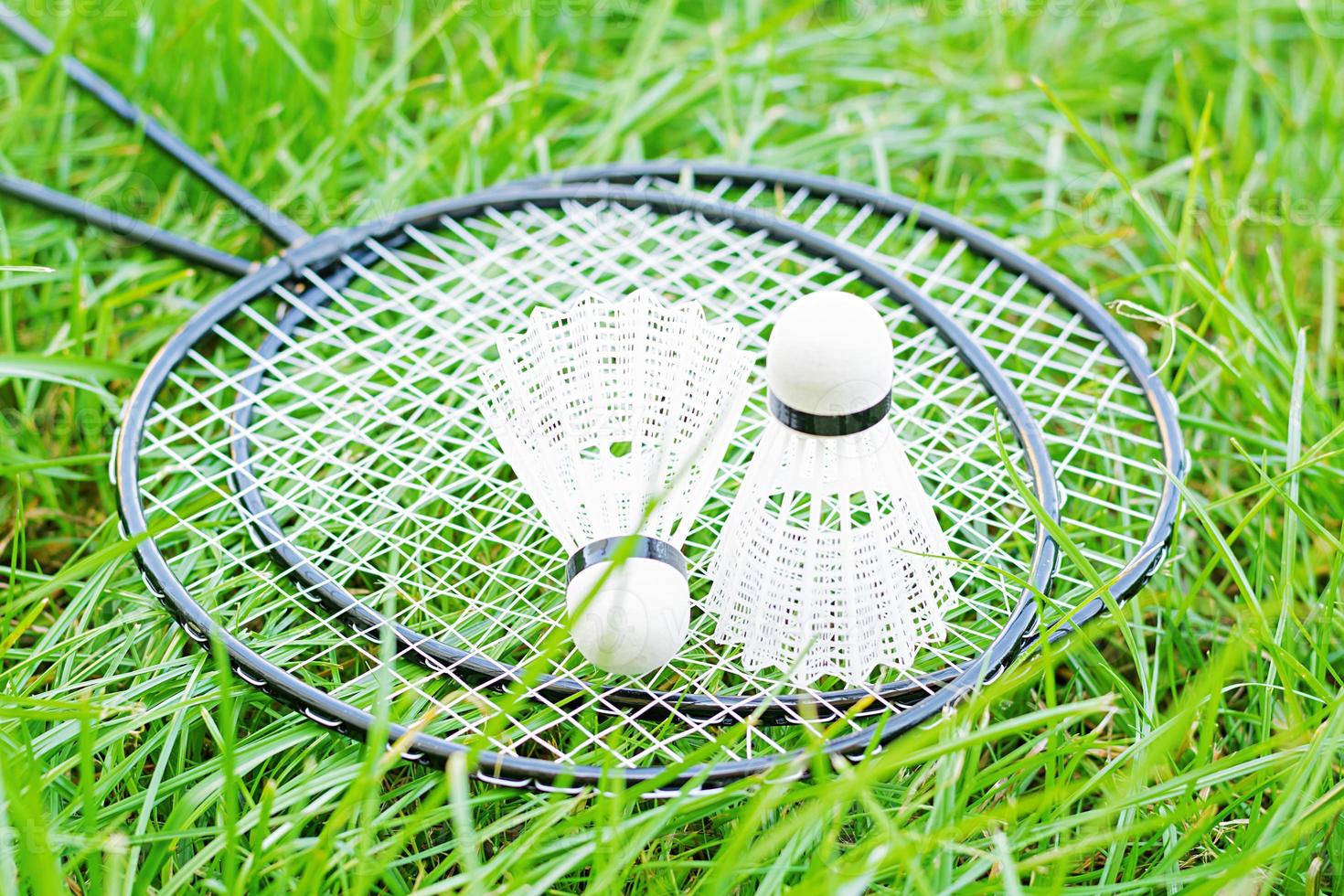 Shuttlecock and badminton rackets on a green lawn photo