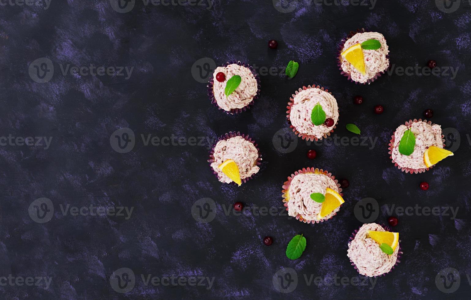 Lemon cupcakes with cherry cream. Cranberry, mint leaves. Food on a dark background. Top view photo