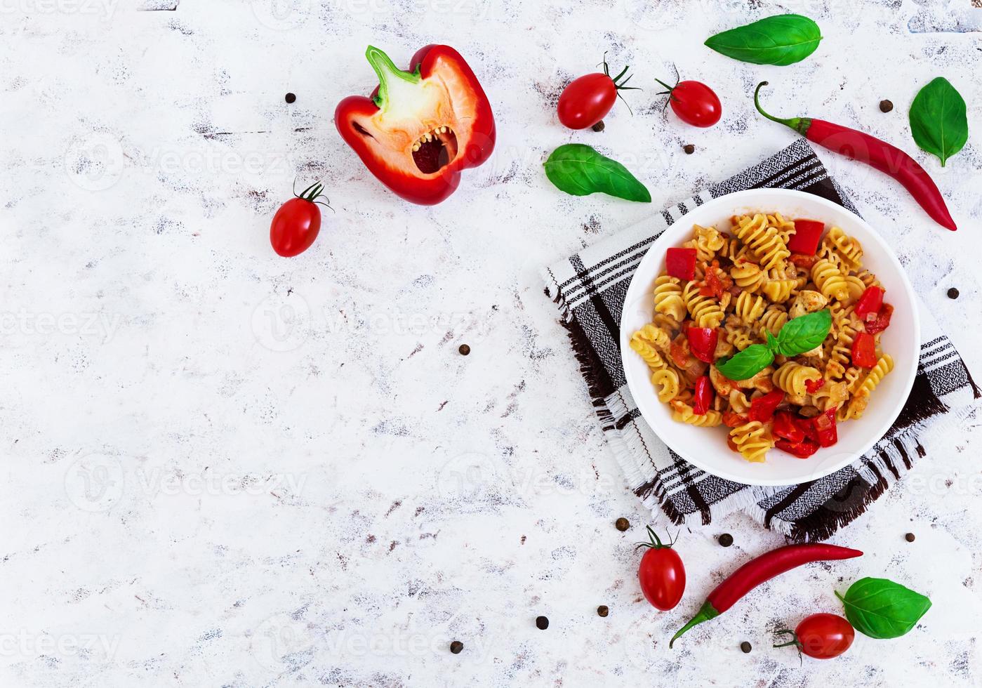 Radiatori pasta with chicken and peppers on white background. Top view photo