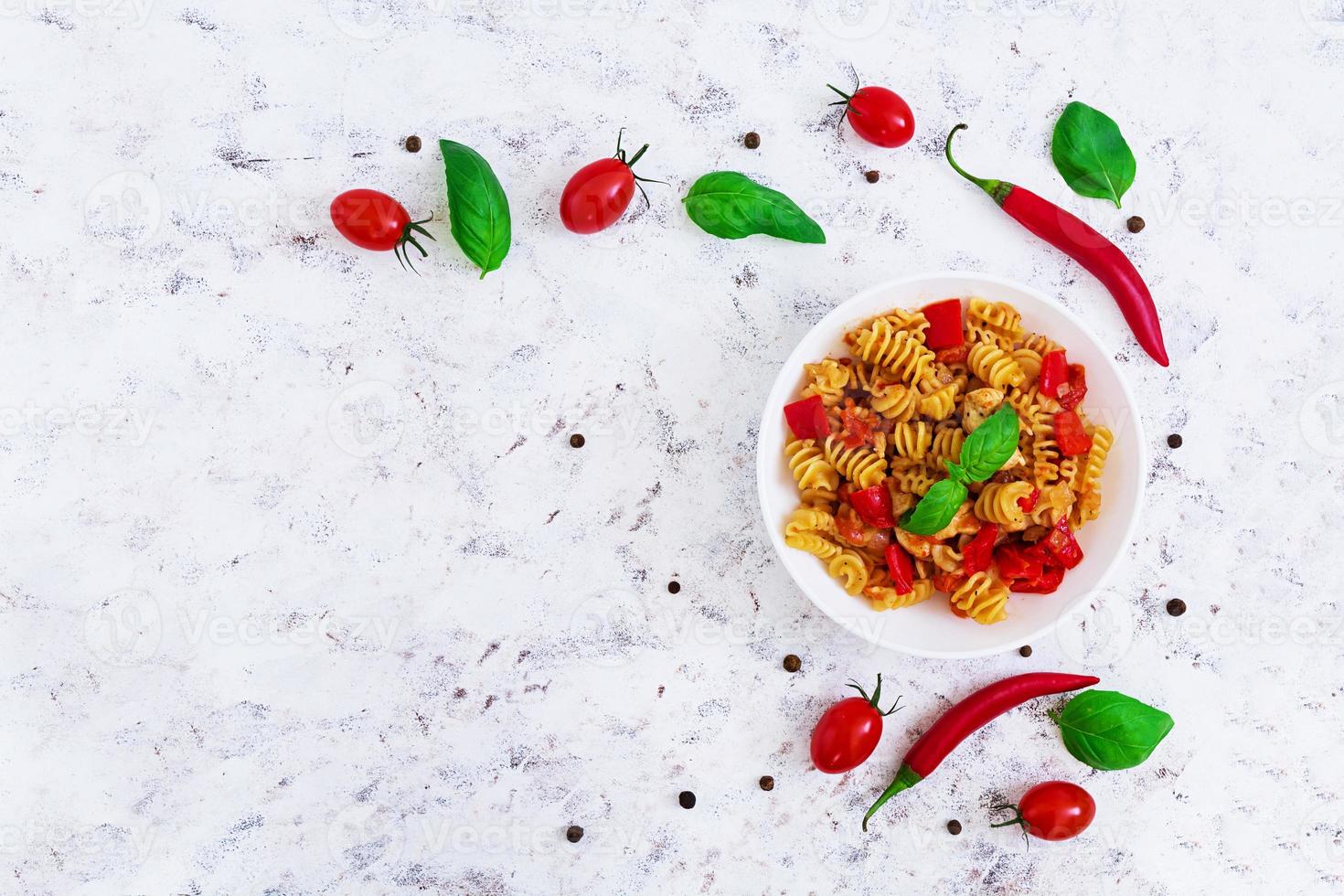 Radiatori pasta with chicken and peppers on white background. Top view photo