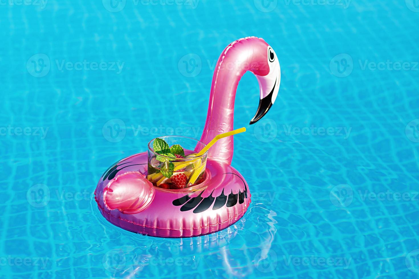 Fresh coctail mojito on inflatable pink flamingo toy at swimming pool. Vacation concept. photo