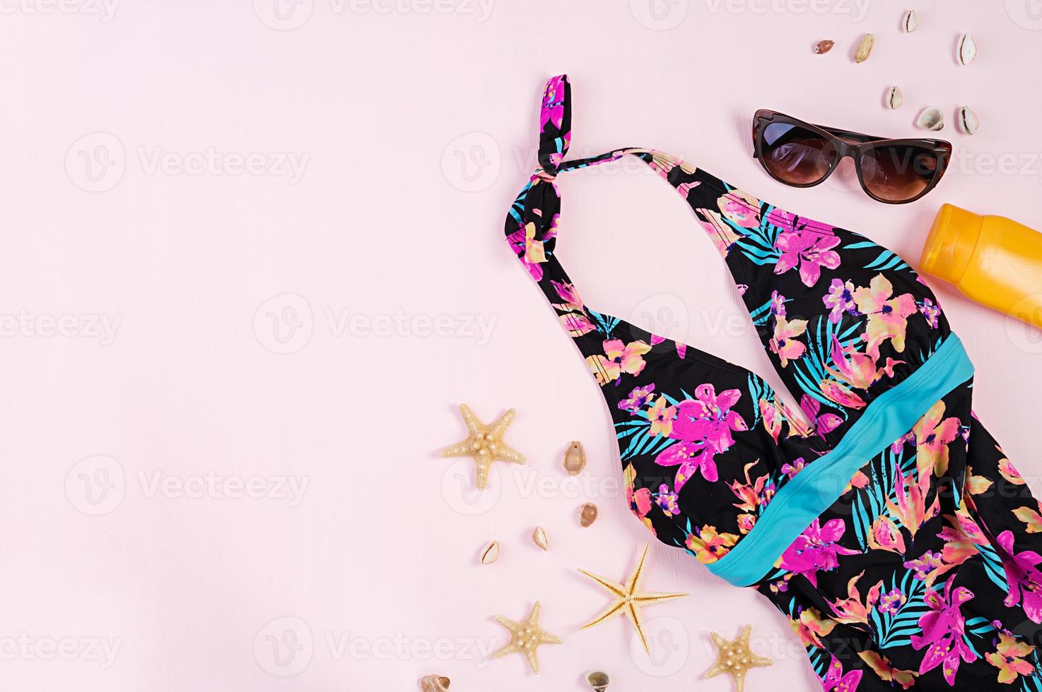 Swimsuit with different seashells and starfish on pink background. Top view photo