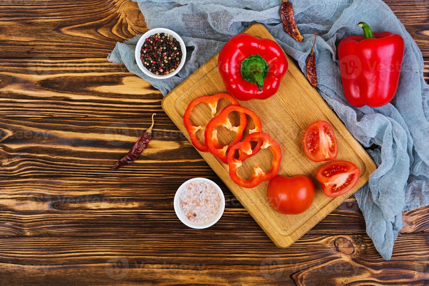 pimienta, tomate, sal, especias diferentes sobre fondo de madera foto