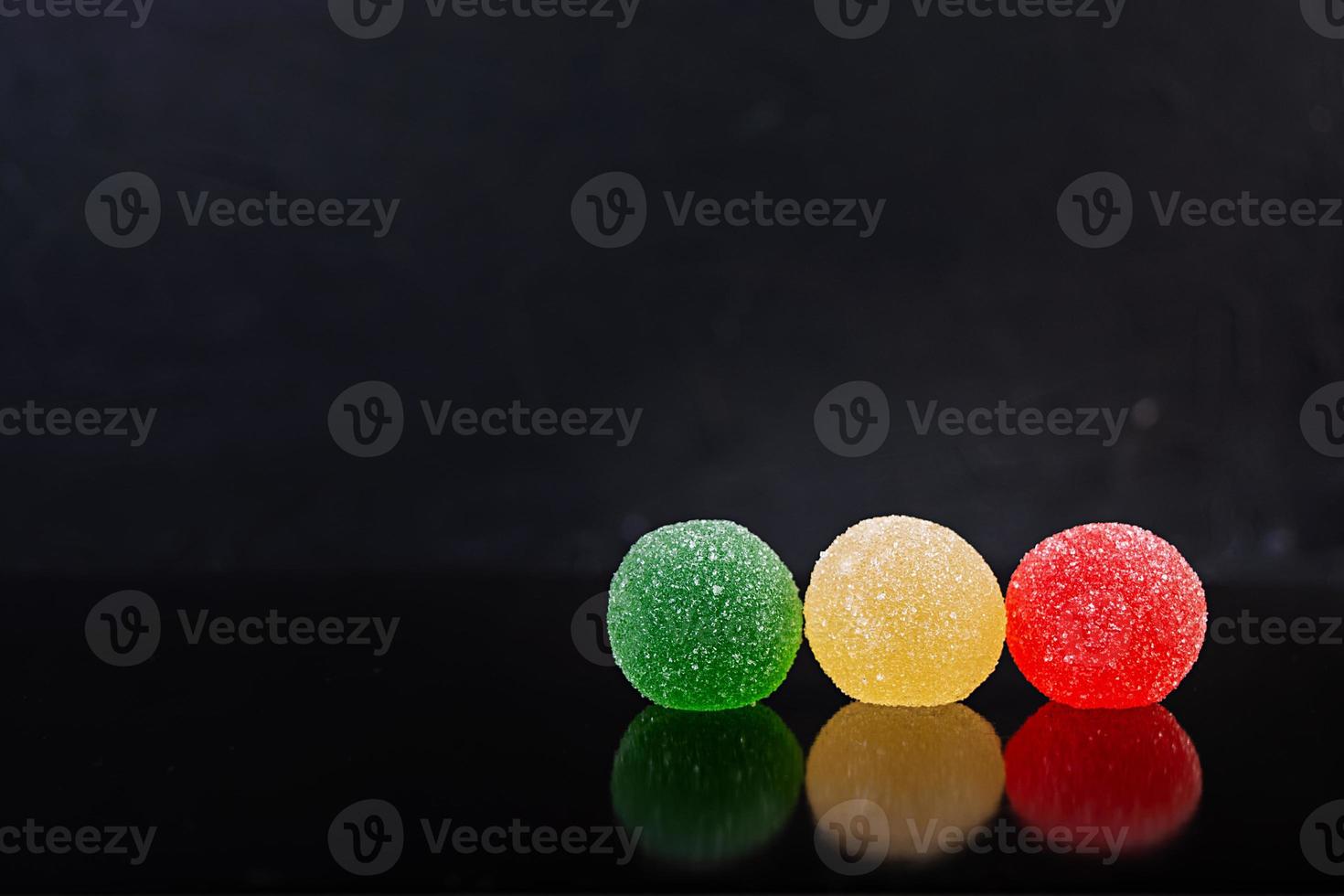 Colorful marmalade isolated on dark background. Delicious jujube balls. photo