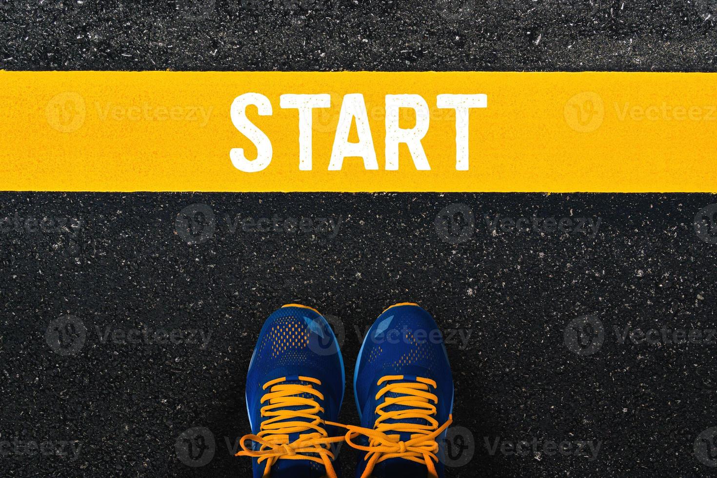 word Start on yellow line with blue sneaker or sport shoes on asphalt road background. photo