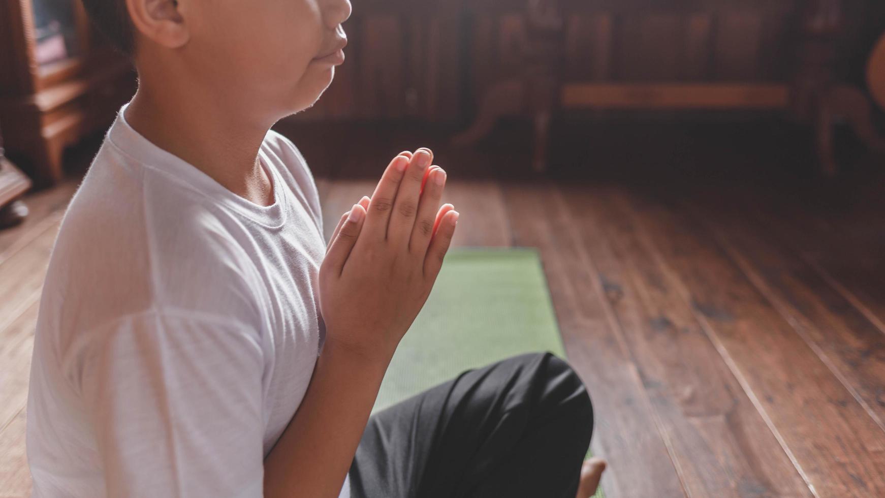 niño meditando con las manos en posición de oración foto