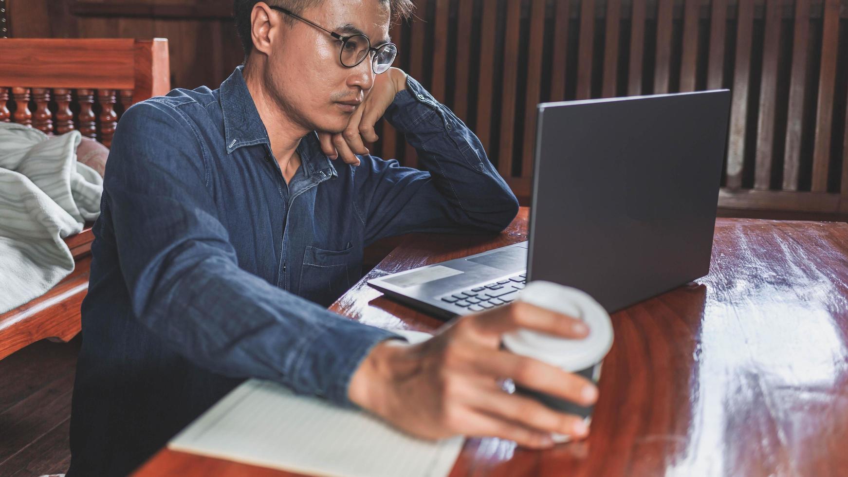 Business man teleconference from home business man in meeting using his laptop computer and writing notes photo