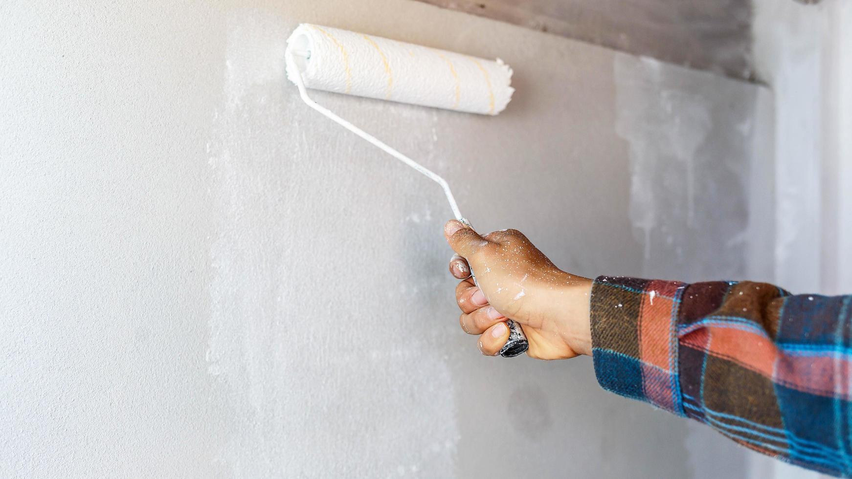 hand of a painter holding a plot to paint the white wall photo
