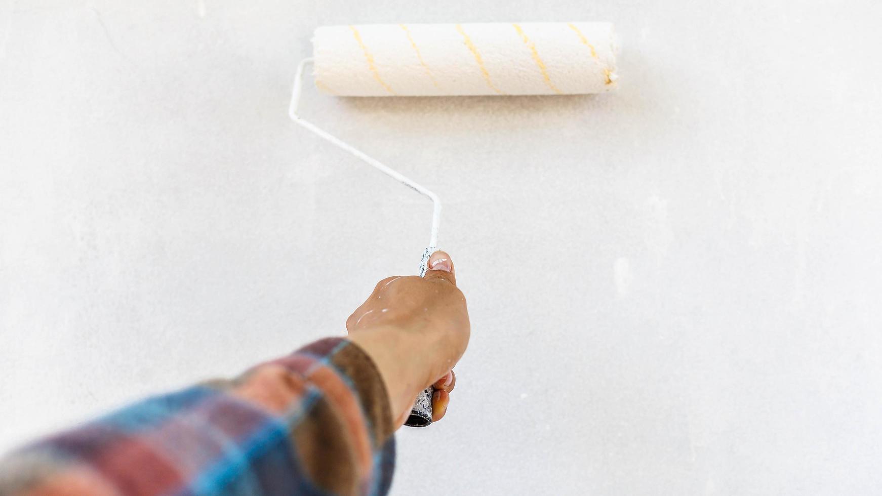 hand of a painter holding a plot to paint the white wall photo