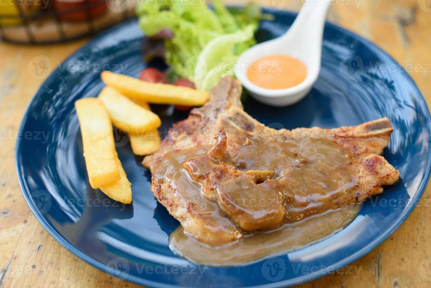 Pork chop french fries sot on a blue plate on a wooden table photo