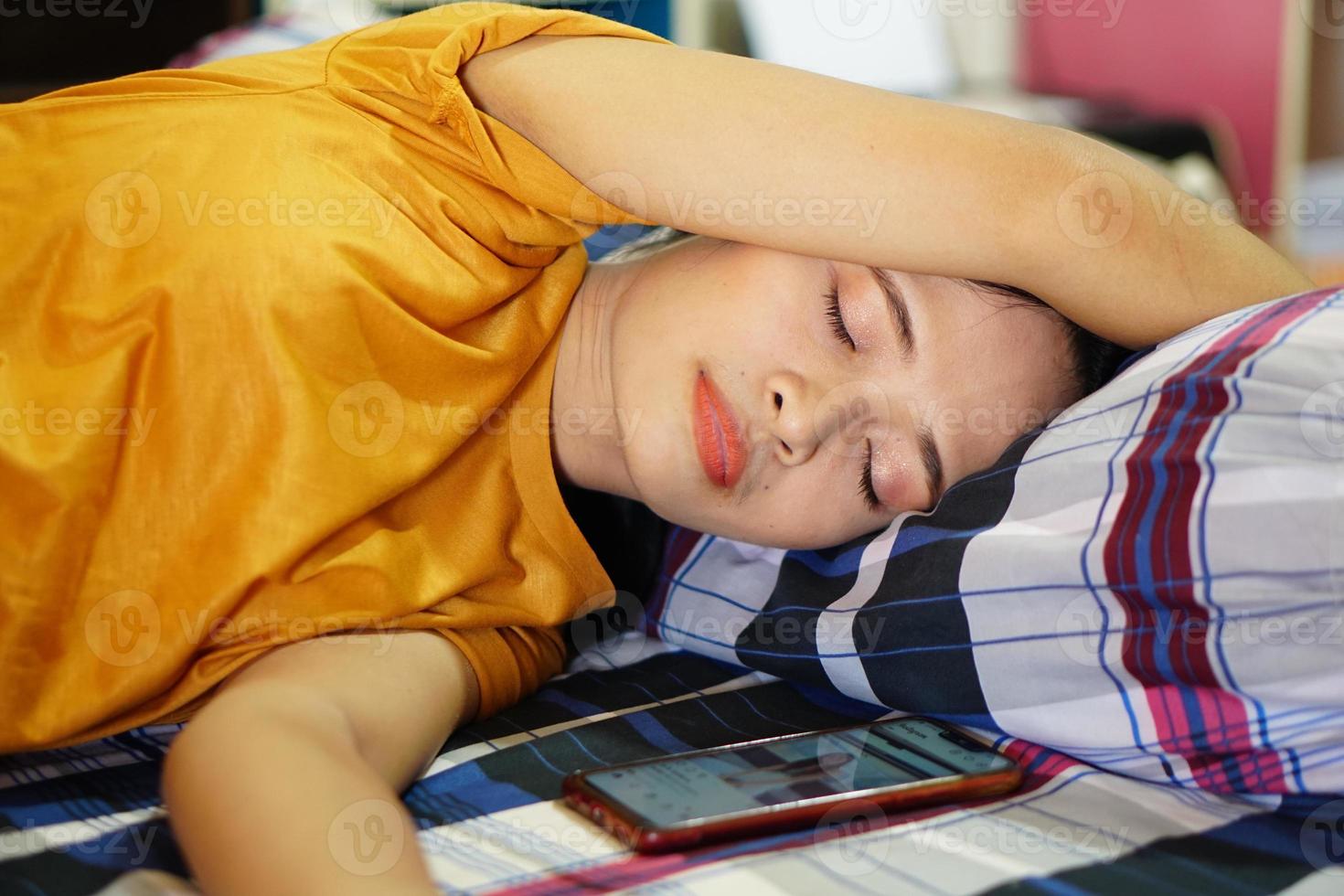 mujer asiática con camisa naranja durmiendo cansada después del trabajo foto
