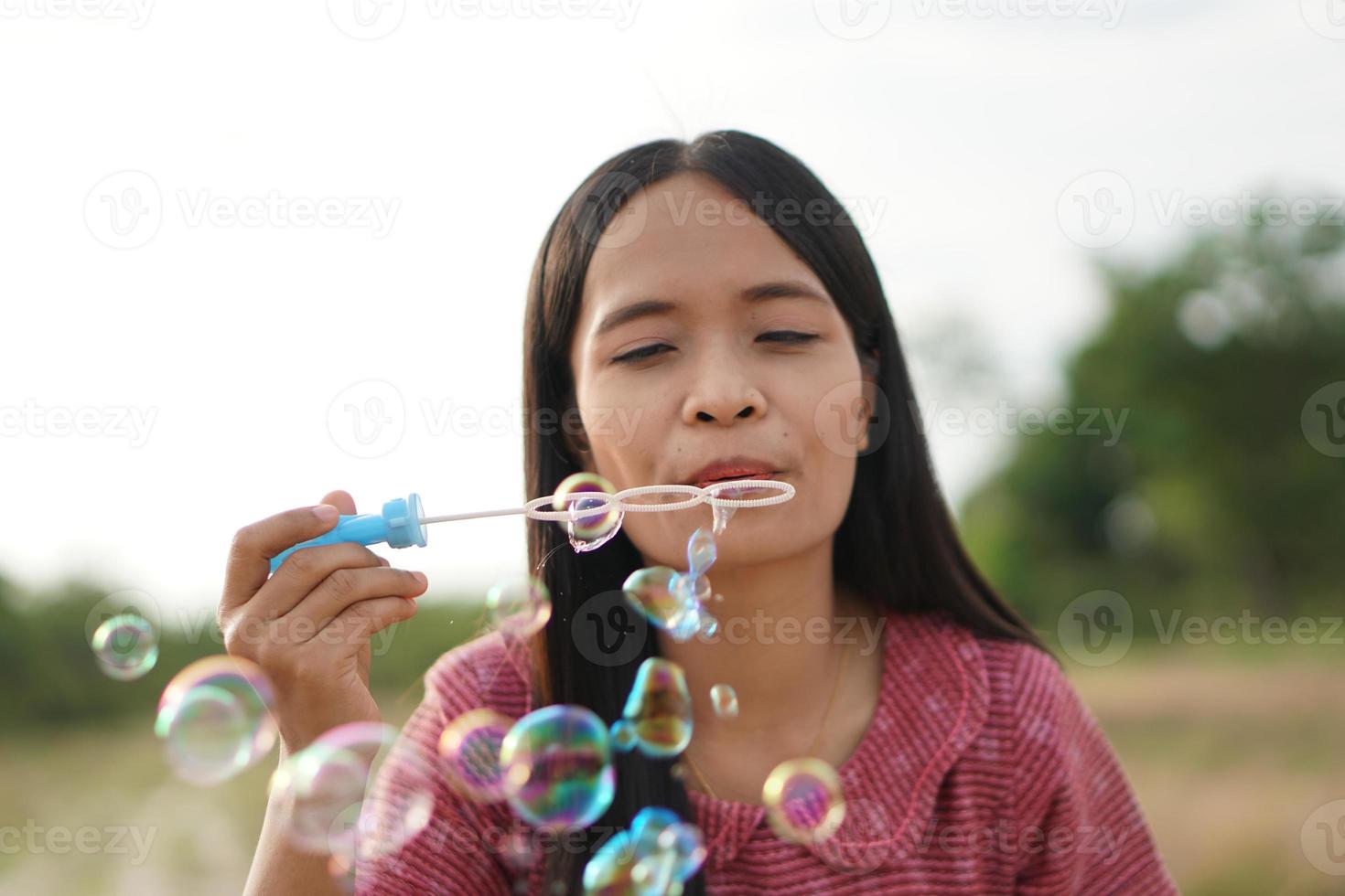Asian woman blowing soap bubbles every green grass background photo