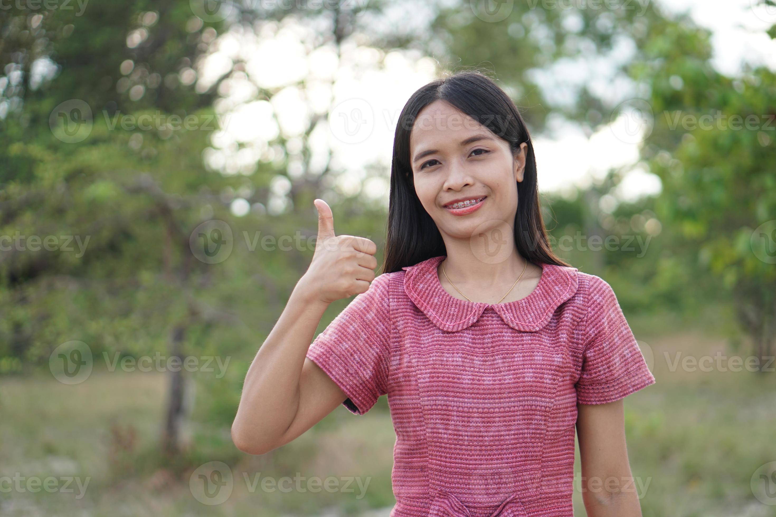mujer asiática sonriendo alegremente levanta la mano hacia el fondo de la naturaleza del cielo foto