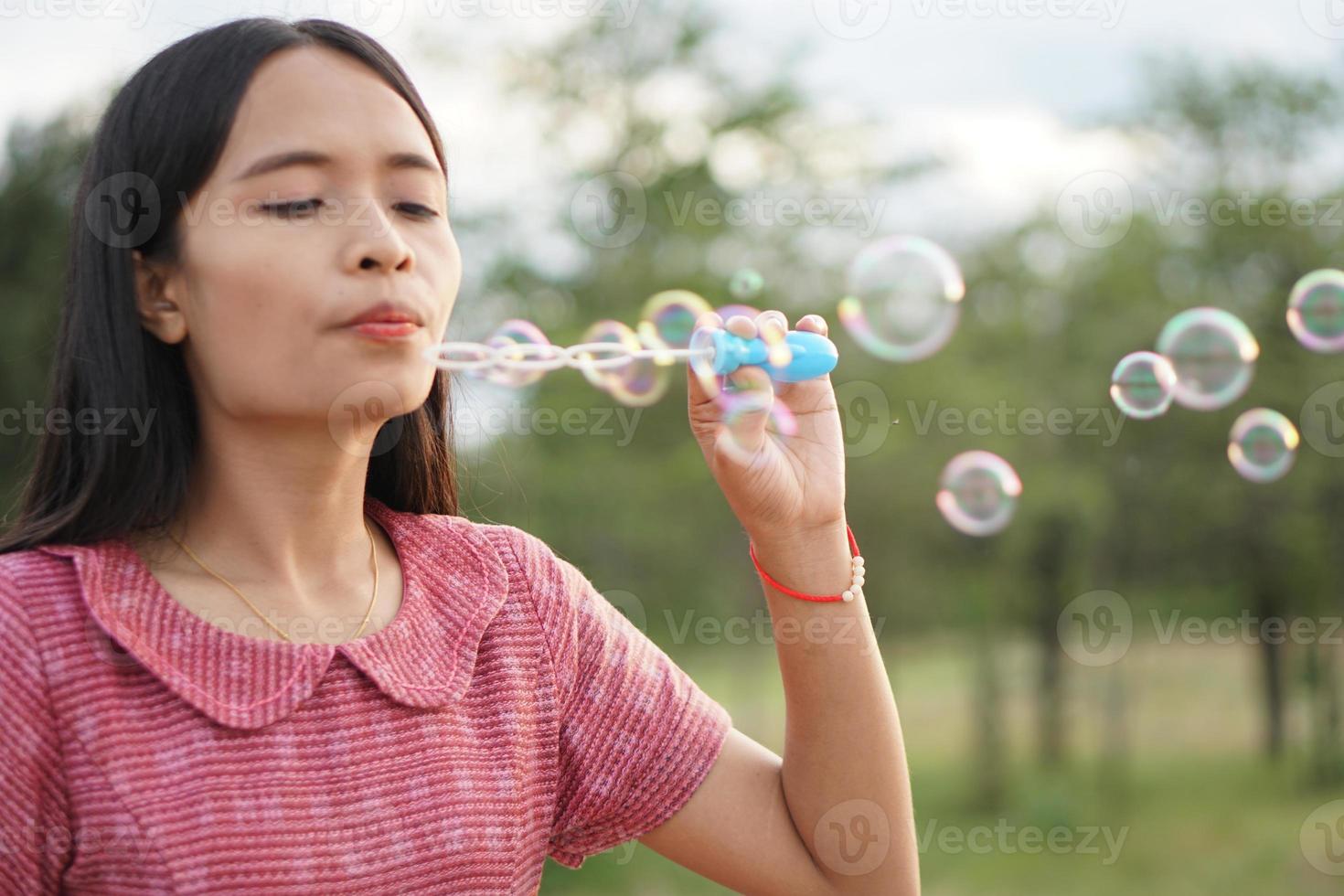 Asian woman blowing soap bubbles every green grass background photo