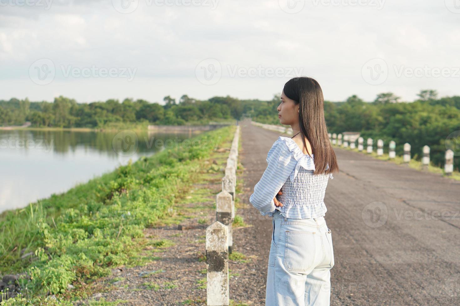 Asian woman in a light blue dress is walking happily in the middle of the meadow. photo